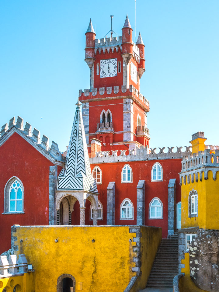 Sintra Pena Palace red clock tower with stairs and yellow walls.