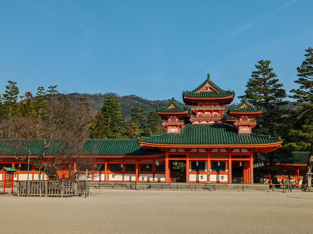 Kyoto Heian Shrine exterior with empty rocky courtyard and trees in background.