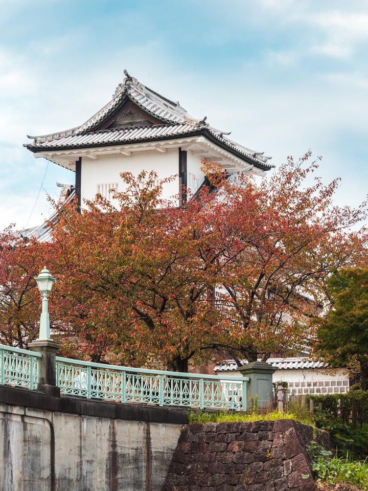 Kanazawa Castle behind bridge and trees.