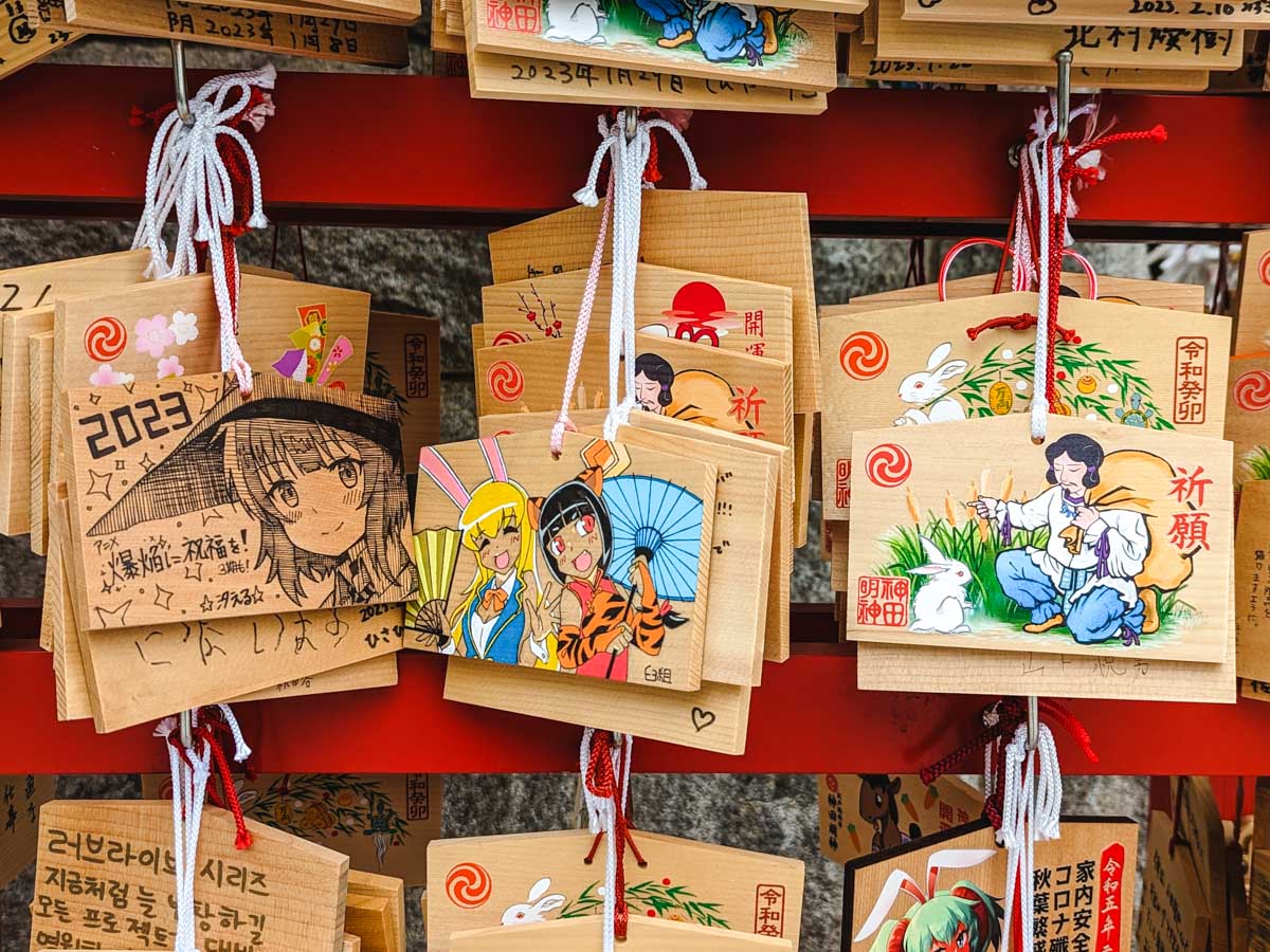 Closeup of ema boards with various illustrations of manga and folklore characters.