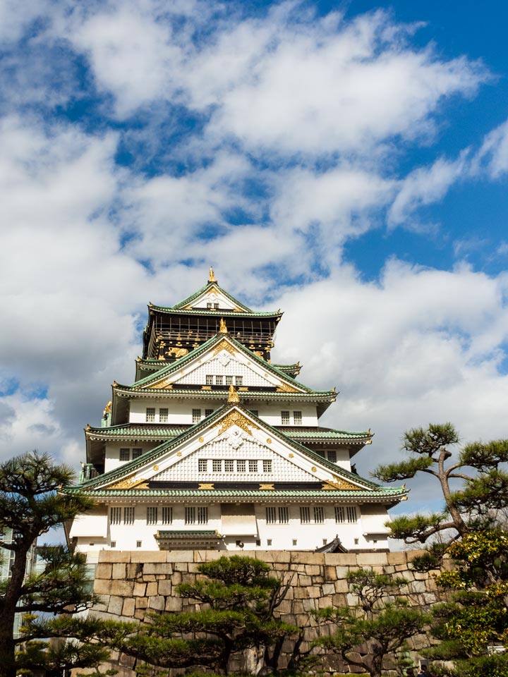 Front of Osaka Castle against partly cloudy sky.