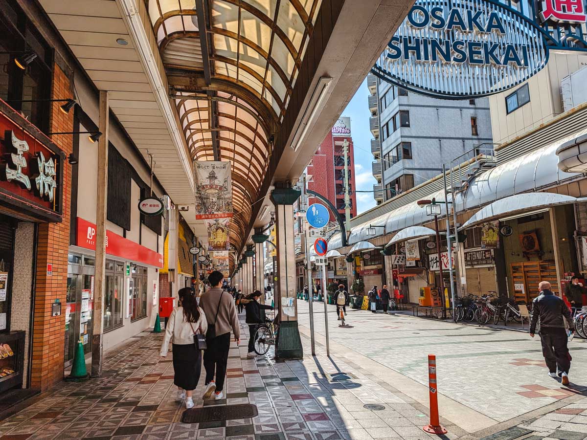 Osaka Shinsekai street with covered shopping arcade and pedestrians.