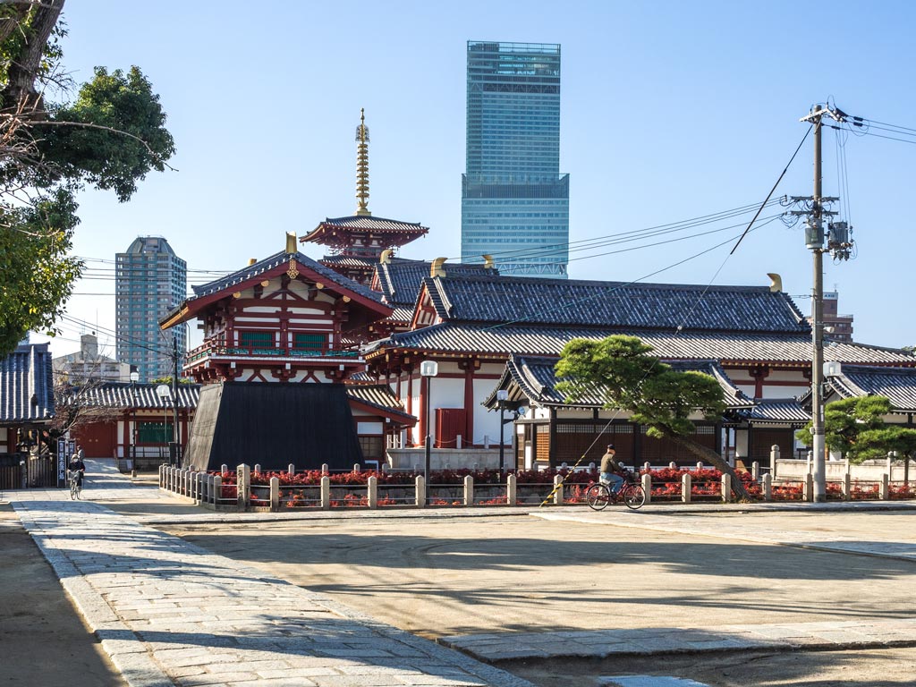 Osaka Shittenoji Temple red and white exterior with two skyscrapers rising in the distance.