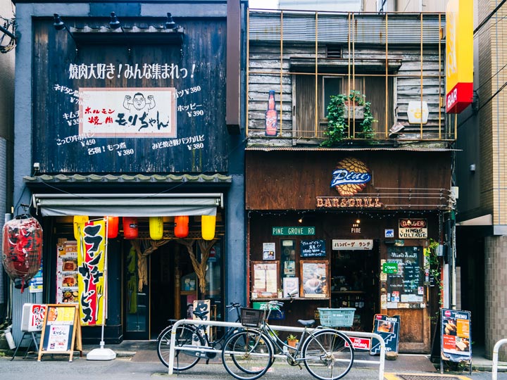 Blue and brown facades of old Tokyo cafes with bikes out front.