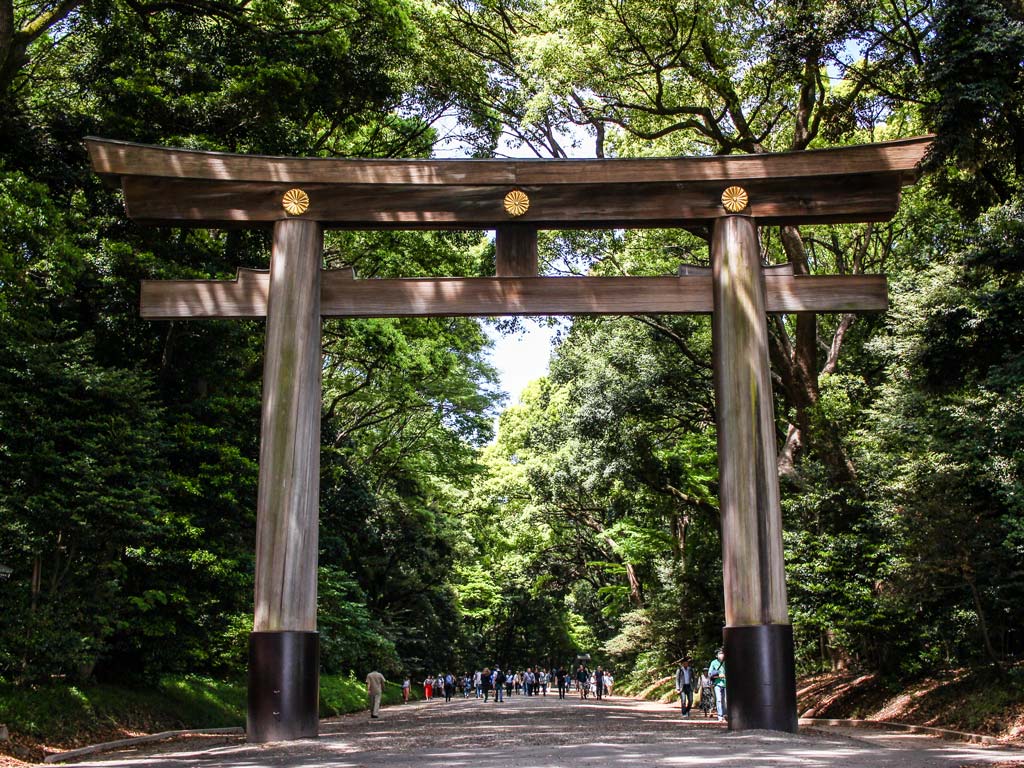 Large wooden torii gate over path through forest in Yoyogi Park Tokyo.