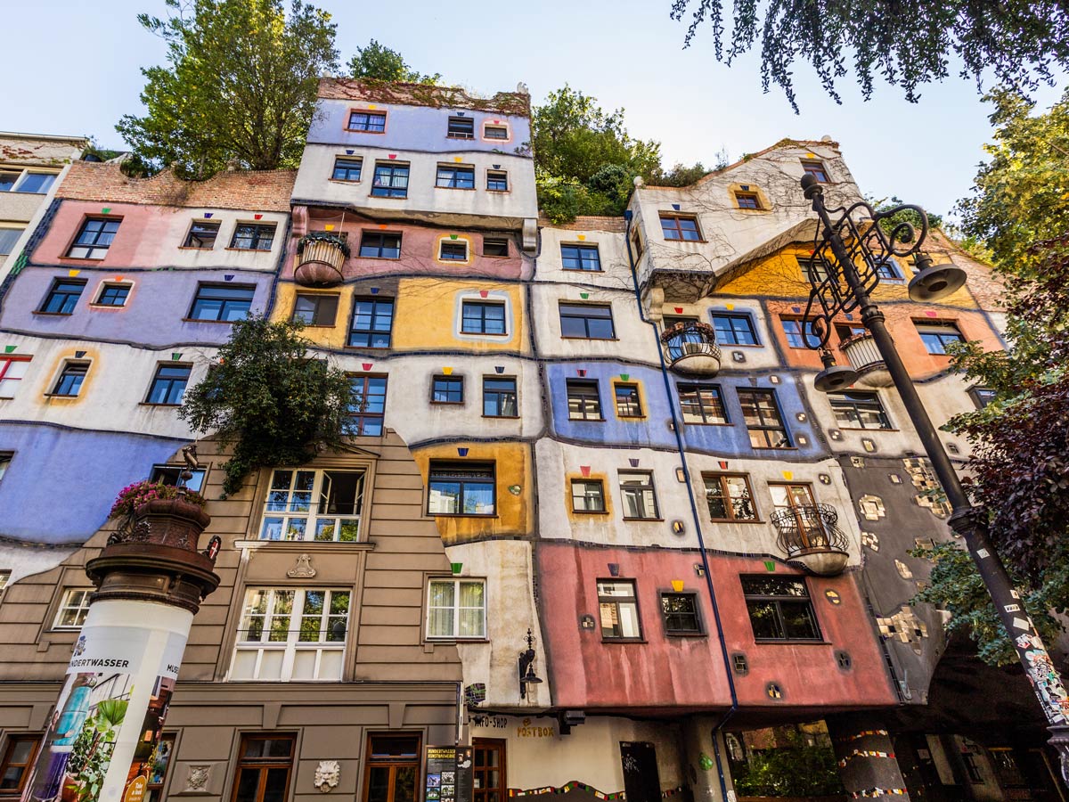 Exerior of Hundertwasserhaus in Vienna with colorful walls and numerous windows.