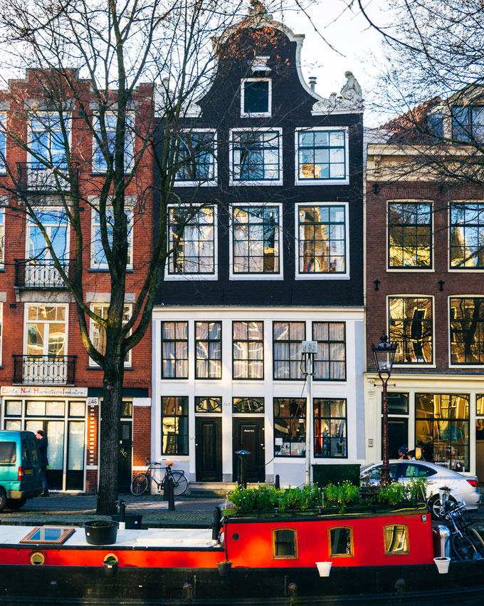 Canal houses and red houseboat in Jordaan, a popular spot for 2 days in Amsterdam.