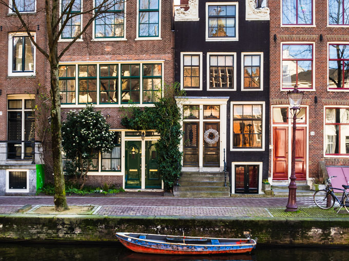 Amsterdam canal houses with blue and red rowboat.