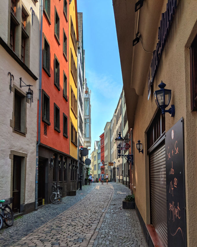 Cobbled alley in Cologne old town with colorful facades on either side.