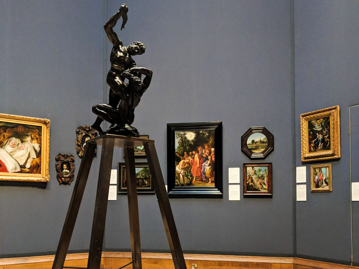 Exhibit room inside Scottish National Gallery with five oil portraits and black statue of man.