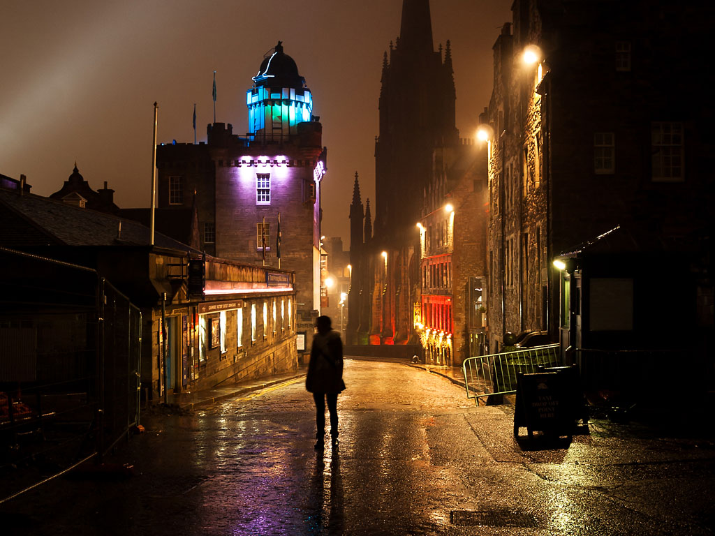 Person walking along dark street in Edinburgh old town.