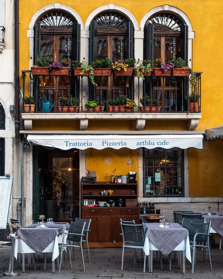 Venice cafe with yellow facade and outdoor seating at Campo Santo Stefano.