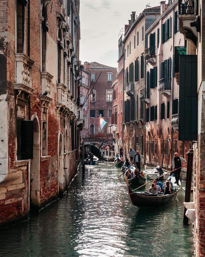 Gondolas passing along canal with old brick facades