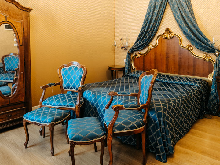 Venice Hotel Locanda Canal bedroom with blue bed and chairs.