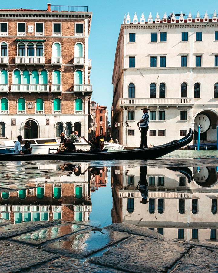 Gondola and background buildings reflected in puddle at Mercato di Rialto.