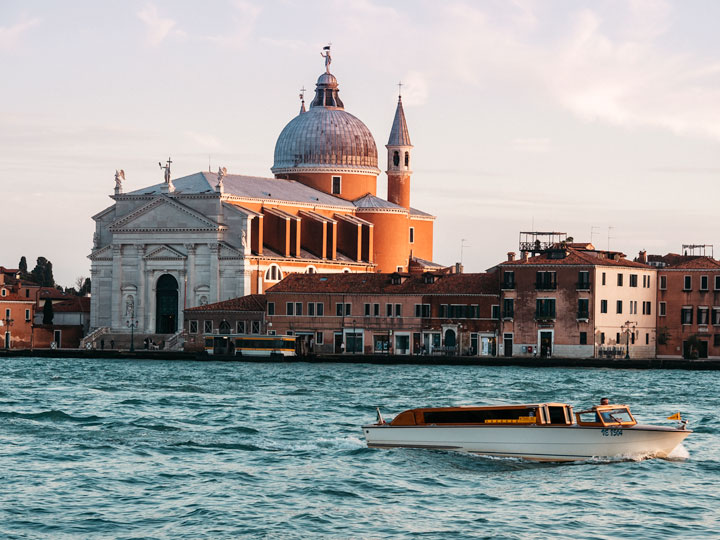 Sunset view of San Giorgio Maggiore and speedboat in Venice along canal.