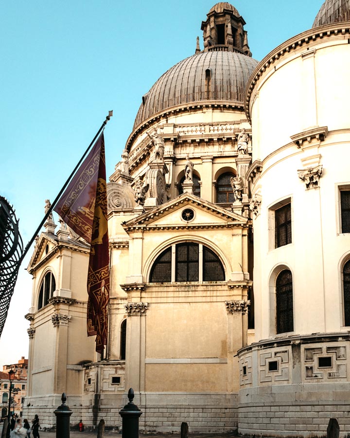 Exterior of Basilica di Santa Maria della Salute in Venice with Venetian flag.