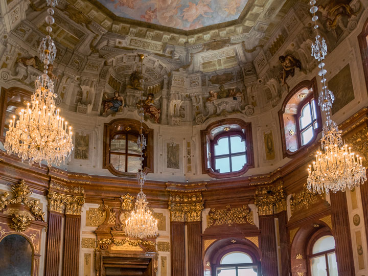 Interior of Schloss Belvedere with three chandeliers and painted mural ceiling.