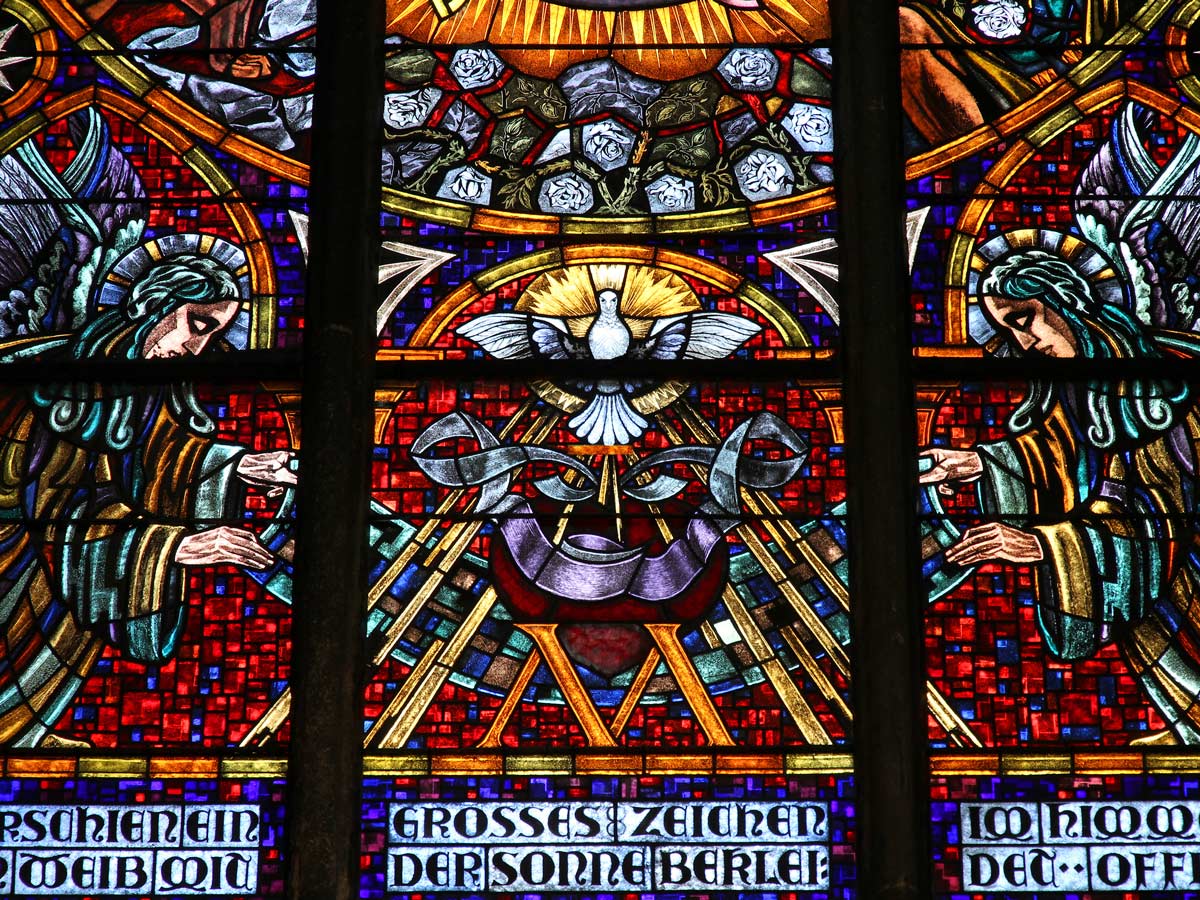 Stained glass windows depicting angels and a white dove inside Vienna Votivkirche.