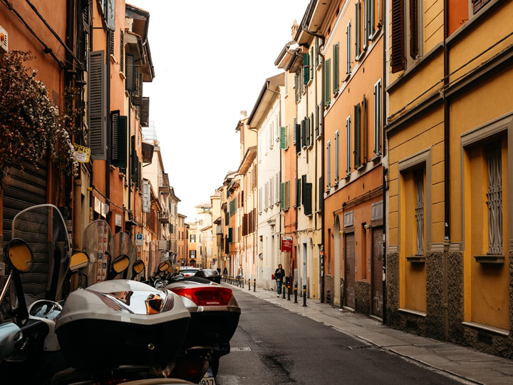 3 days in Bologna itinerary - view of alley with mopeds and yellow orange walls.