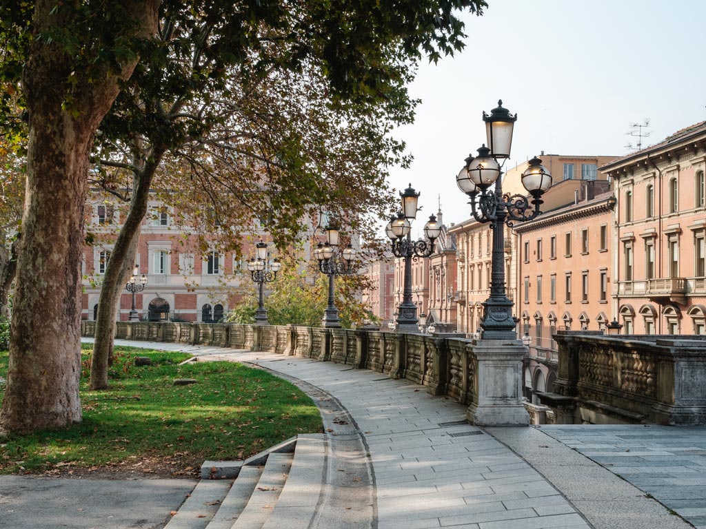 View of park with old lampposts and facades on street.