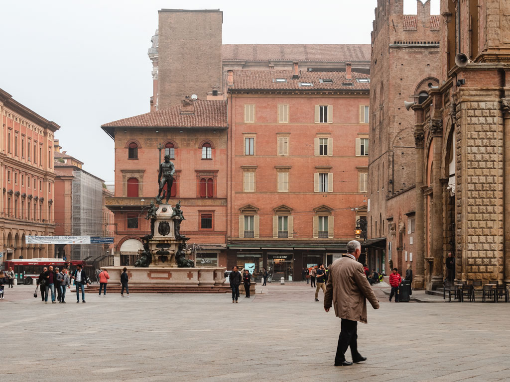 Piazza with statue fountain of Neptune and tourists doing 3 day Bologna itinerary.