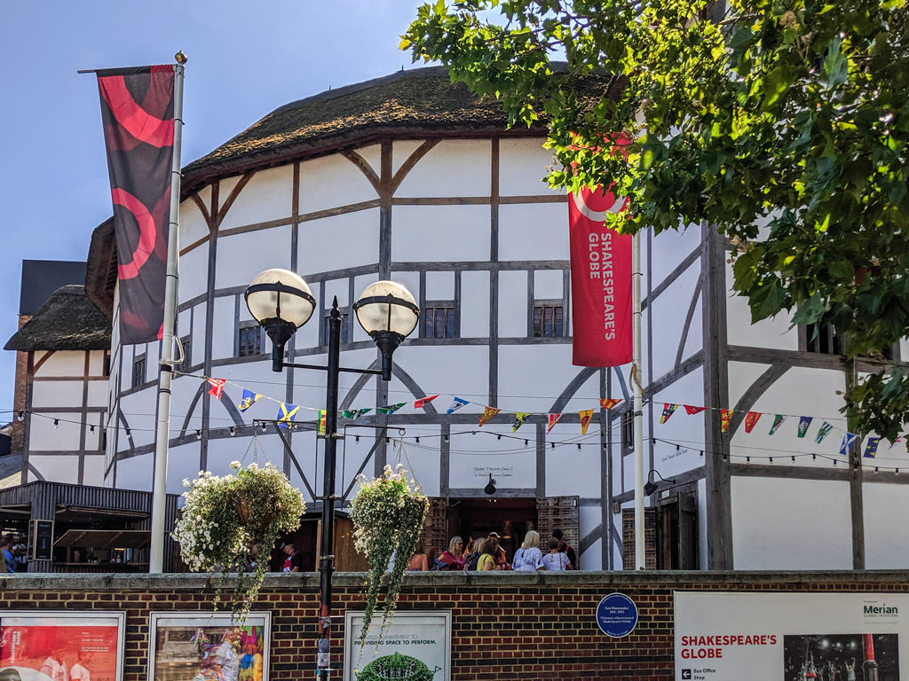 Exterior of Shakespeare's Globe Theatre in London with half-timbered walls and thatched roof.