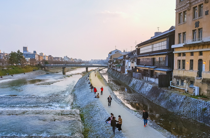 Kyoto Ponto-cho at sunset with people walking along riverside.