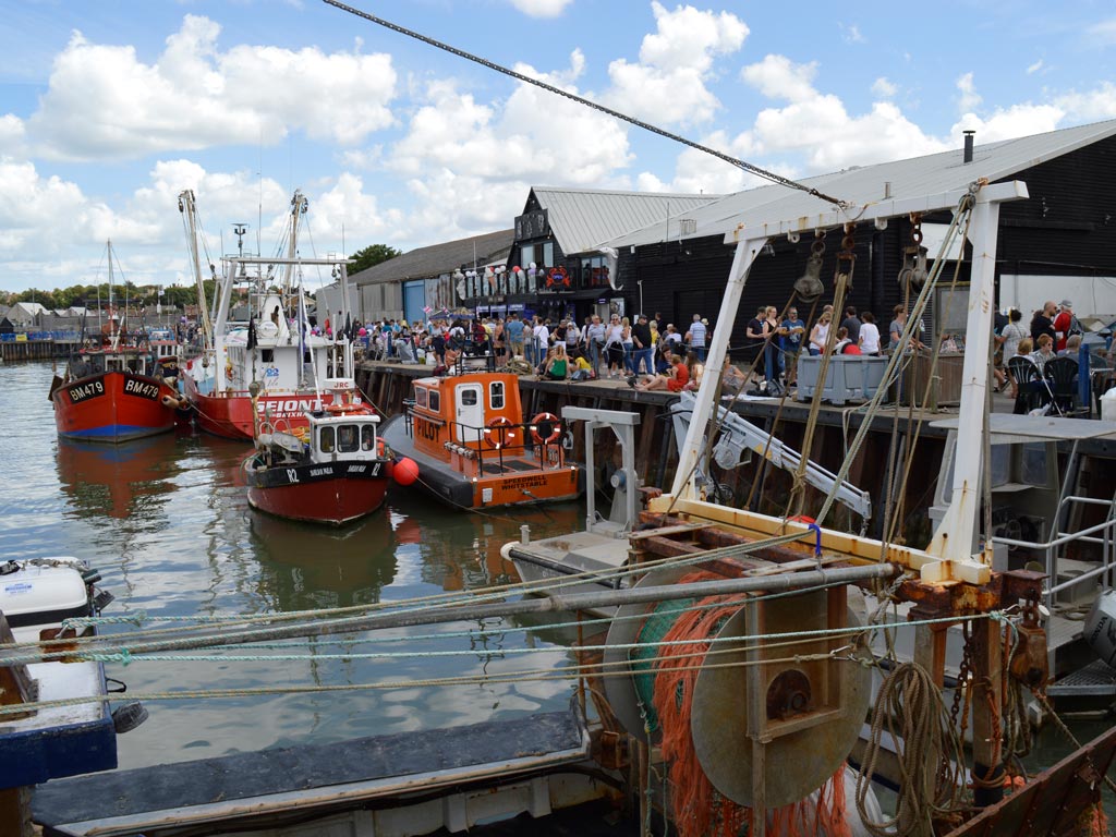 View of Whitstable dock with boats and restaurants.