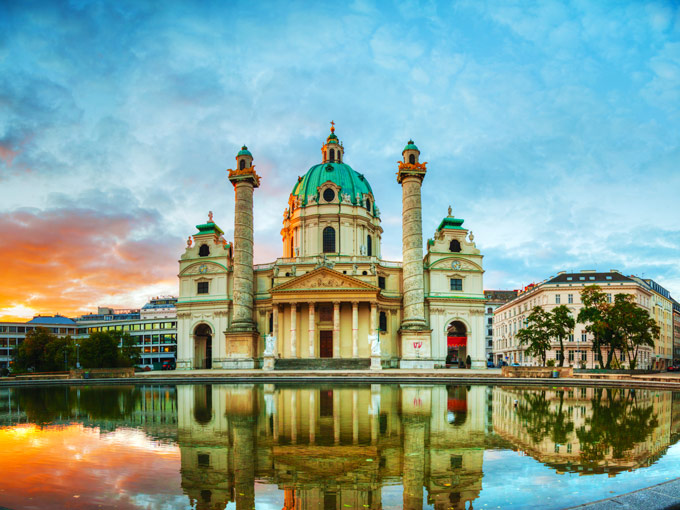 Sunset at domed Vienna Karlskirche with water reflection, an iconic Europe Instagram spot.