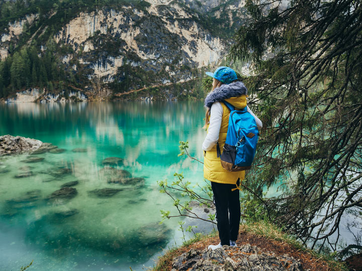 Young woman wearing best gifts for hikers including backpack, vest, and hiking boots.