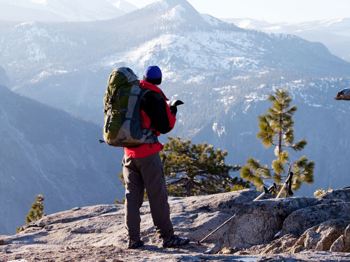 Best gifts for hikers - backpacking man standing on cliff with mountain view.