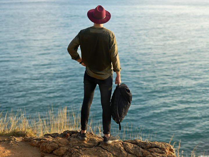 Man wearing best hiking gifts including hat, vest, and water shoes.