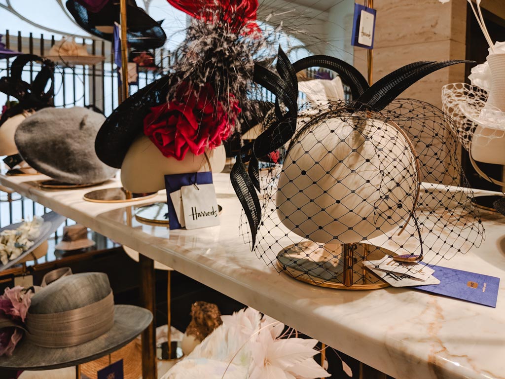 Fancy hats on display inside Harrods department store.