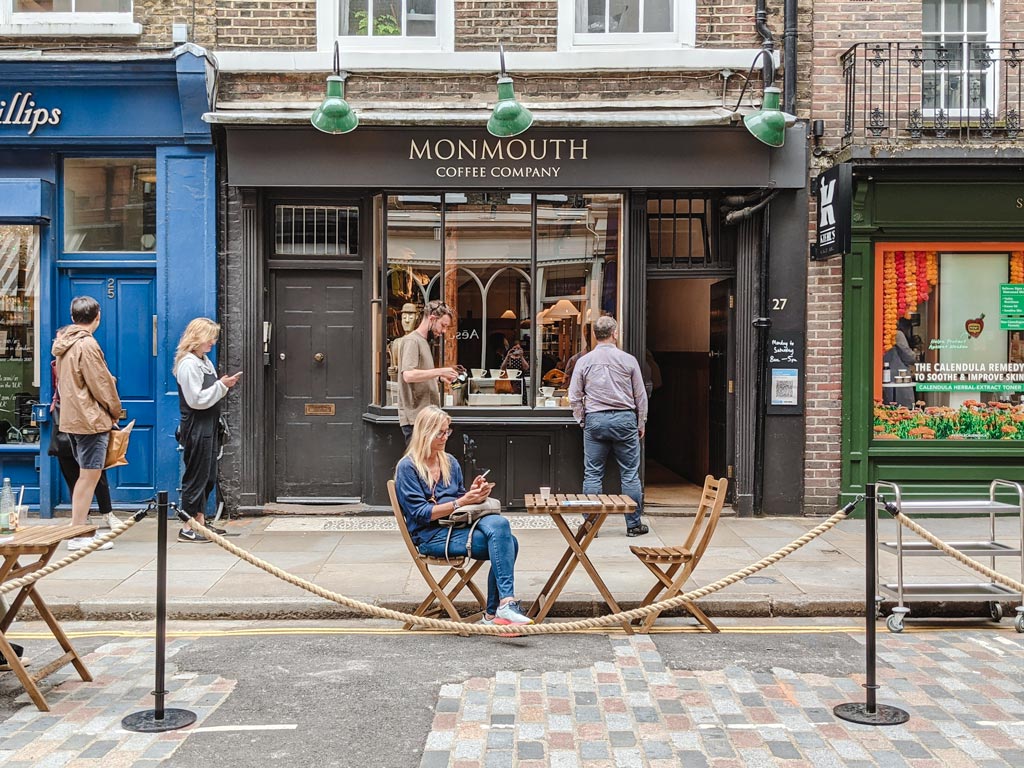 Exterior of Monmouth Coffee shop in Covent Garden with people waiting in line to enter.