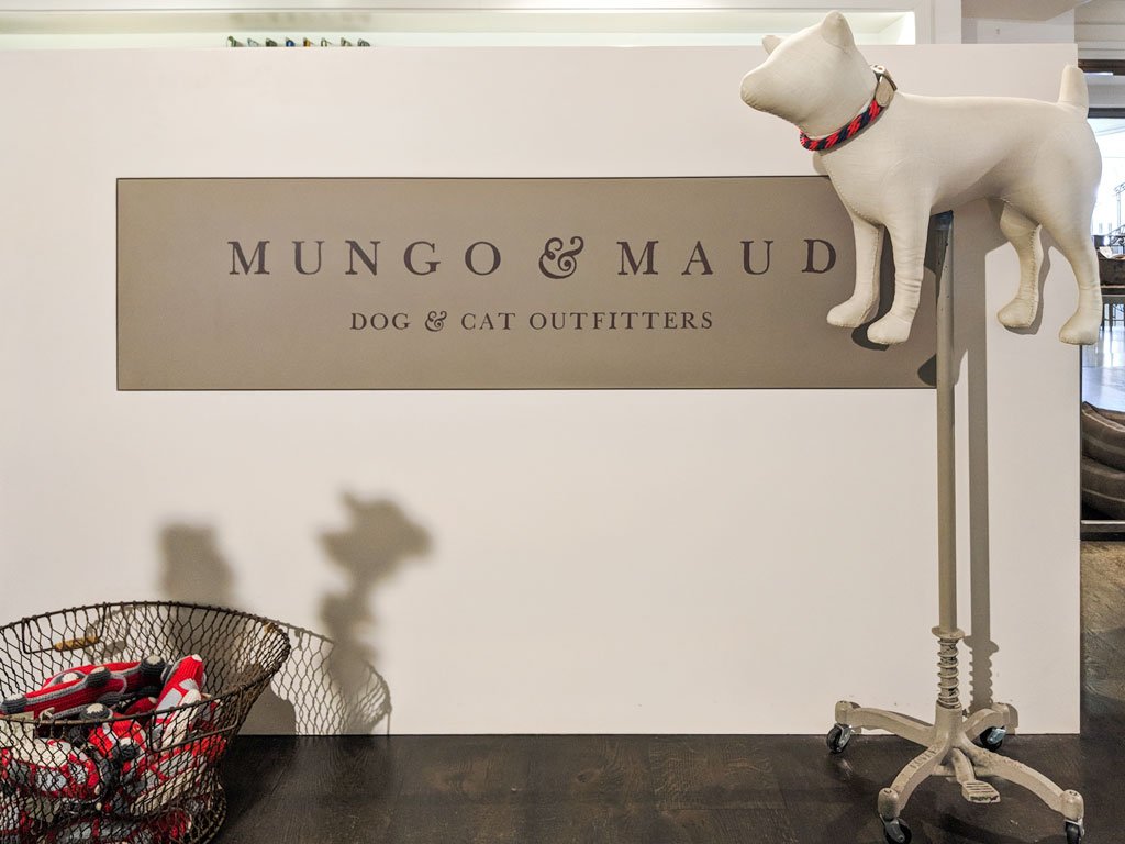 Storefront display of Mungo & Maud with white dog doll on stand.