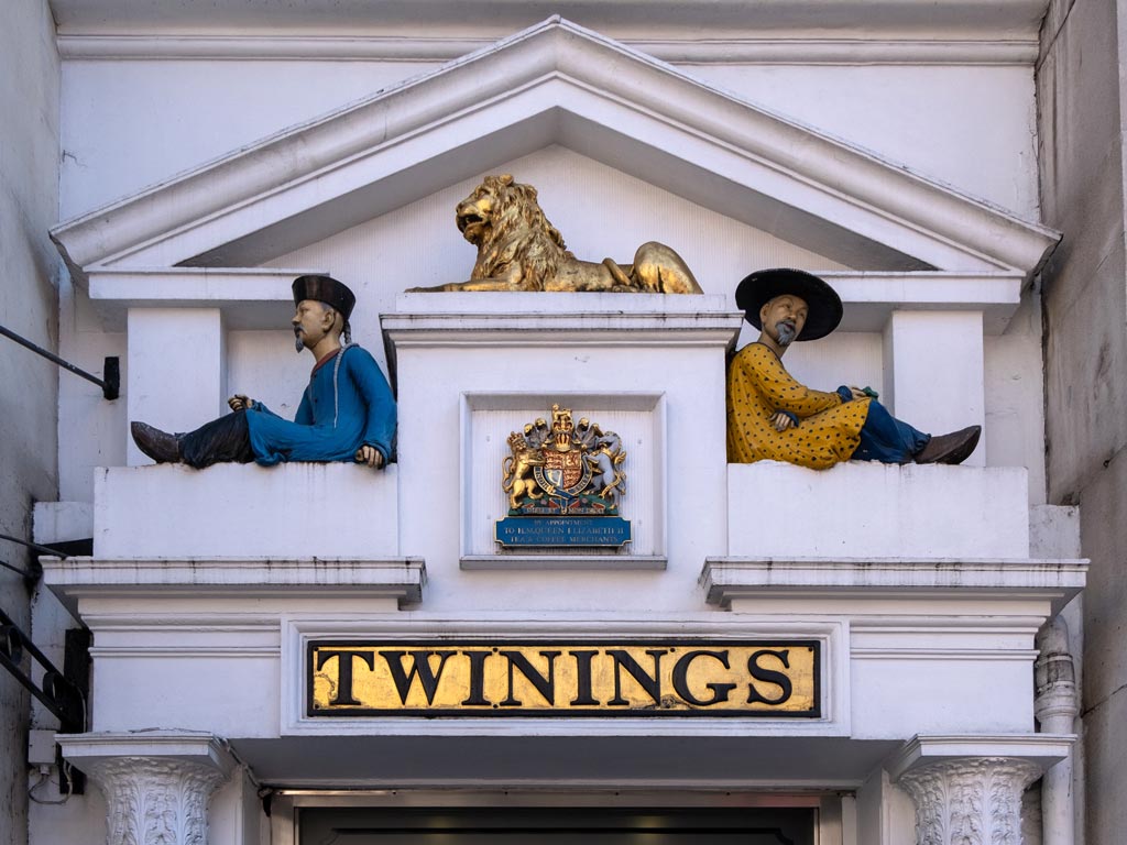 Close-up of Twinings facade with statues of two men and golden lion.