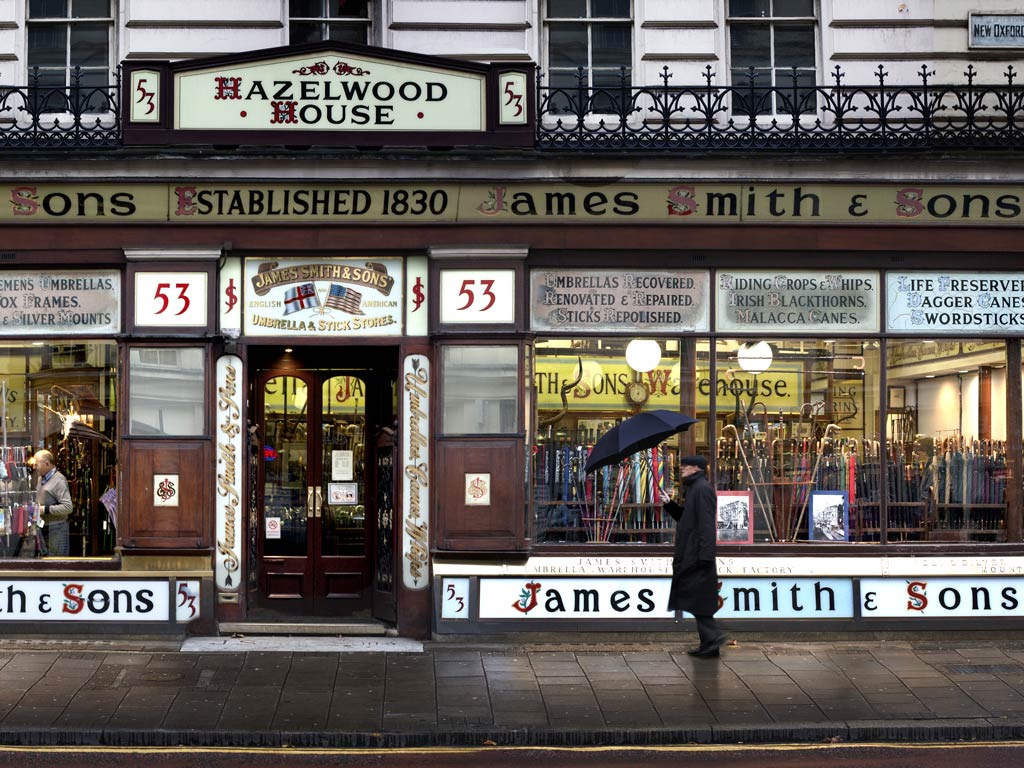 Exterior of James Smith & Sons umbrella store with man holding umbrella outside door.