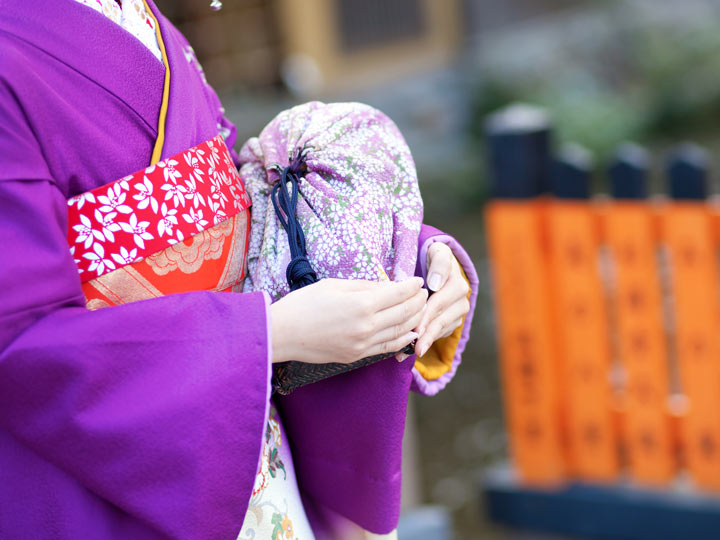 Mannequin in purple kimono holding purple kinchaku bag.