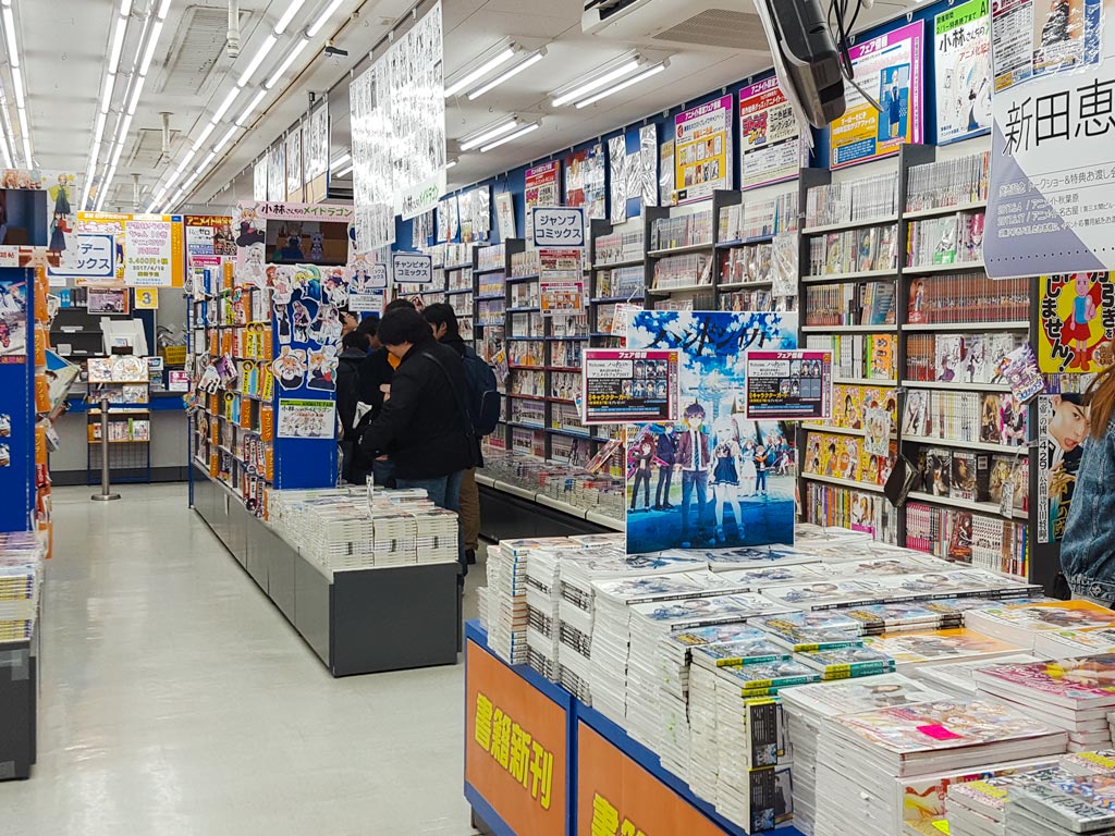 Interior of manga store in Japan with shelves and tables stacked with manga books.