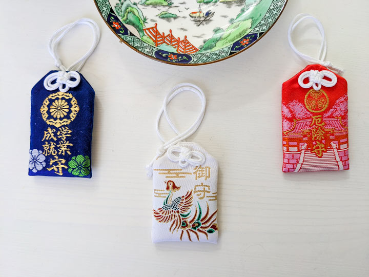 Blue, red, and white omamori Japanese souvenirs with tea saucer.