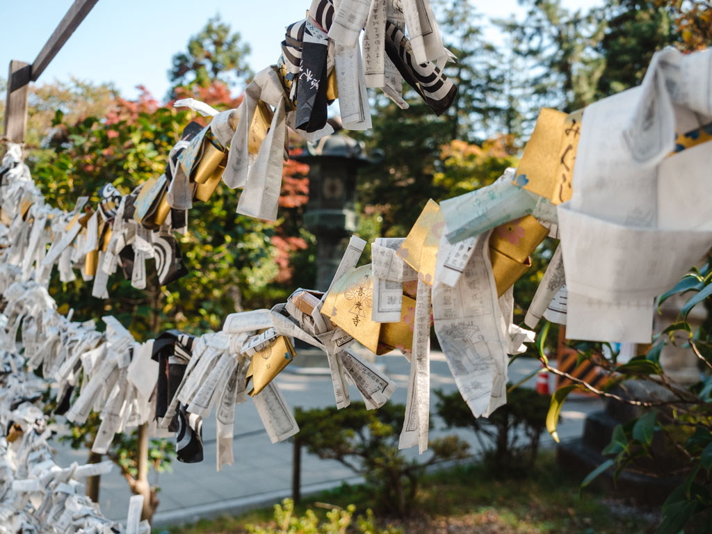 Strands of omikuji paper fortunes hanging in front of trees.