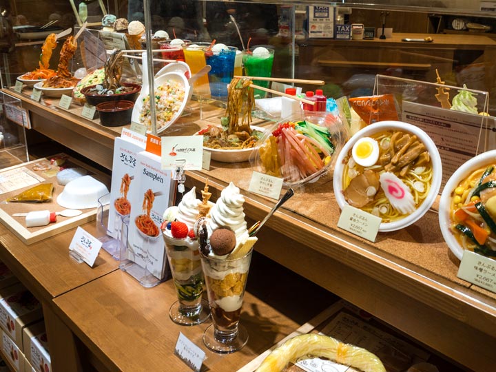 Shelf of Japanese souvenir plastic food displays (sampru), including parfait and ramen.