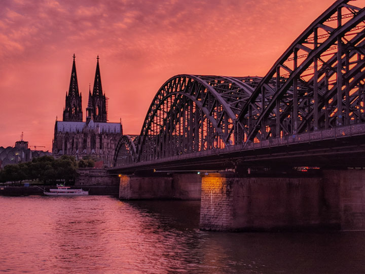 Pink sunset view of Cologne Cathedral and love lock bridge.