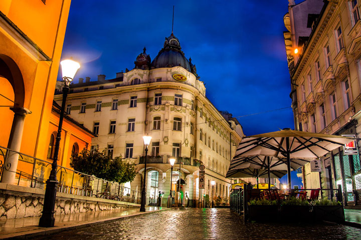 Illuminated hotel and buildings in Ljubljana during winter night.