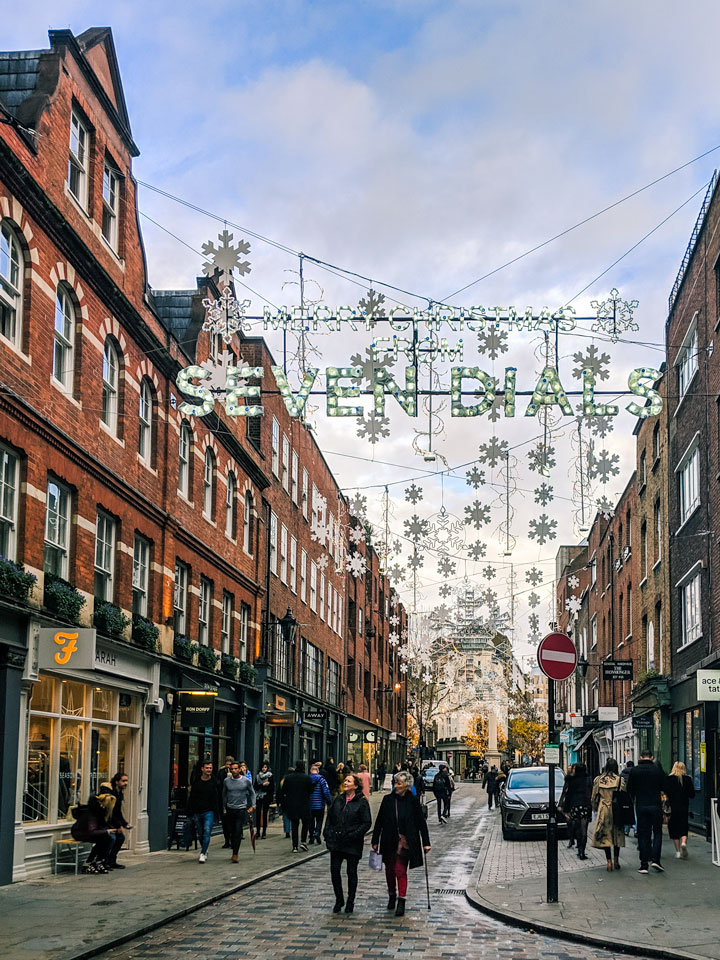 Shoppers walking down illuminated Seven Dials street in London, an excellent choice for winter breaks in Europe.