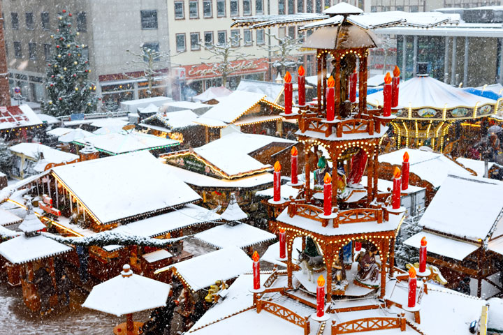 Snow-covered stalls and candle display at Christmas Market in Nuremberg, a popular winter city break in Europe.