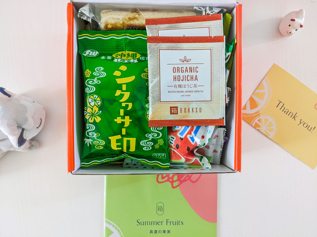 Interior view of Bokksu snack box with organic hojicha packages and lemon cracker snacks on top.