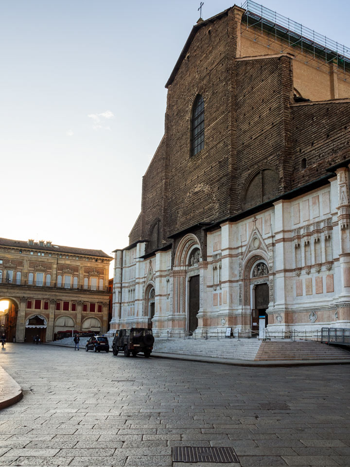 Sunrise view of Basilica di San Petronio exterior with carved marble and brown brick.