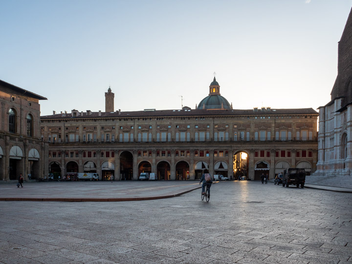 Sunrise at Piazza Maggiore with one cyclist viewed during Bologna itinerary.